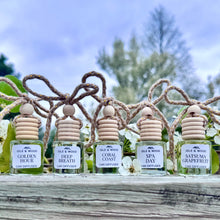 Load image into Gallery viewer, Five small bottles of Idle & Wood car diffusers on a wooden surface with a natural background.