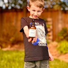 Load image into Gallery viewer, Young boy holding a bottle outdoors in a backyard setting