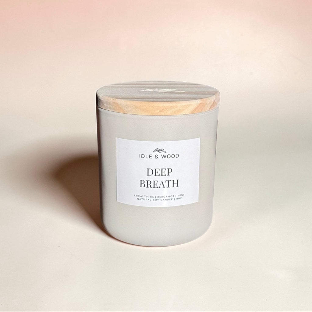 Candle labeled 'Deep Breath' with a wooden lid on a beige background