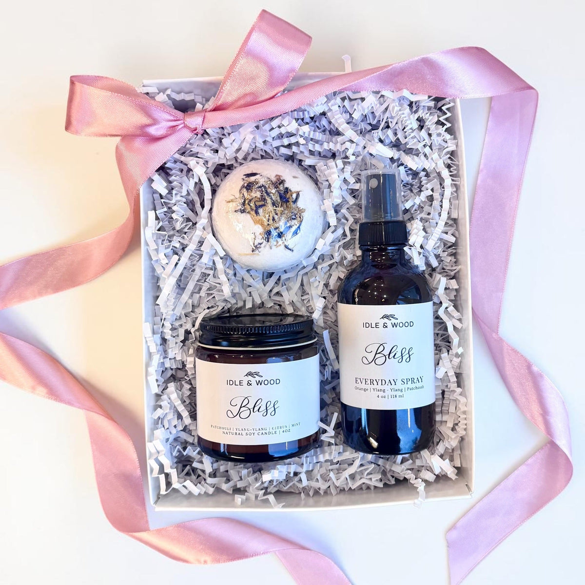 Gift set including a candle, bath bomb and spray in a box with pink ribbon.