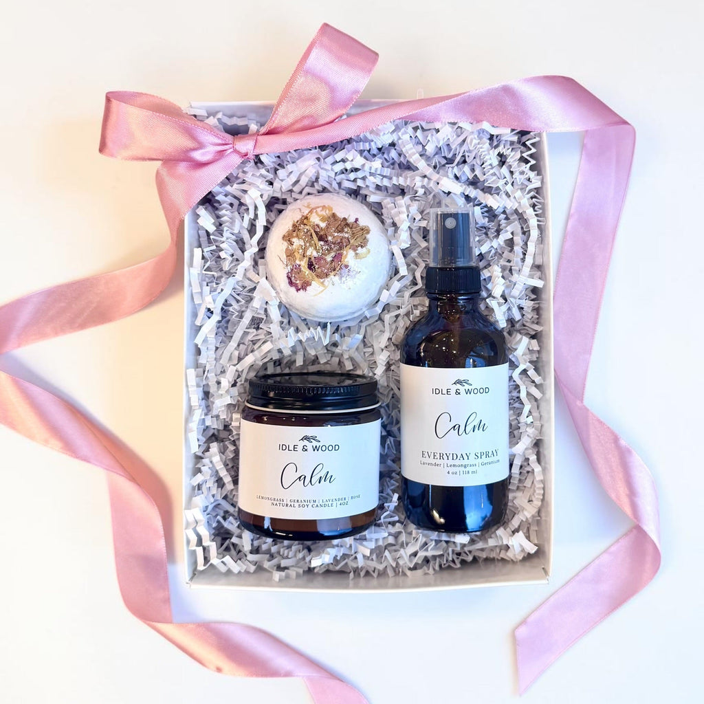 Gift set with a candle, spray, and bath bomb in a box with pink ribbon on a white background